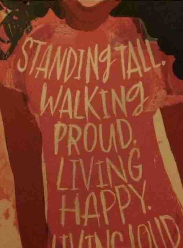 Woman wearing a shirt saying standing tall, walking proud, living happy, living loud