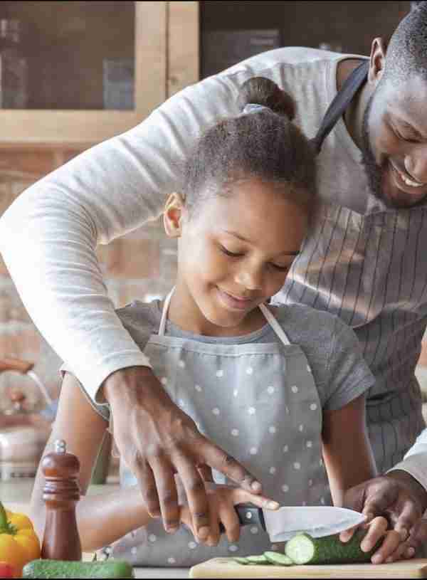 Father chopping vegetables with daughter