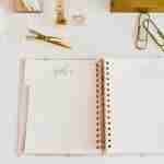 pink planner laying open on a white desk for planner self-coaching resources