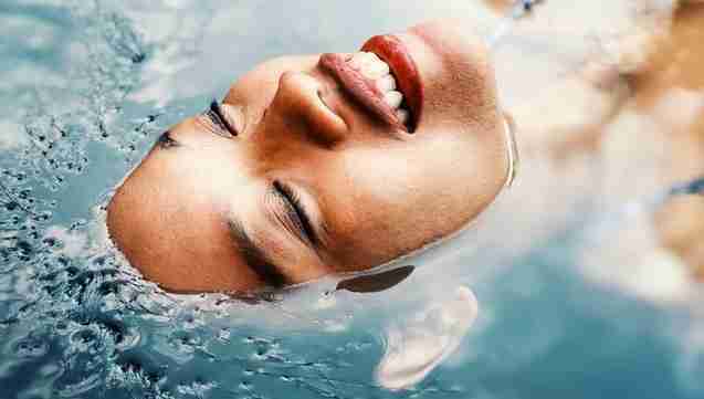woman floating in water as part of her self-care routine