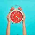 a person holding up a clock demonstrating the benefits of self-coaching includes time saving