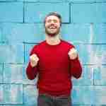 man with head tilted backward and fists raised looking happy