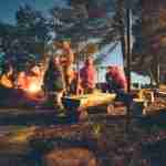 group of people sitting next to a campfire