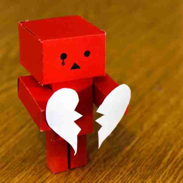 tiny red robot with heart torn in two after a breakup plan