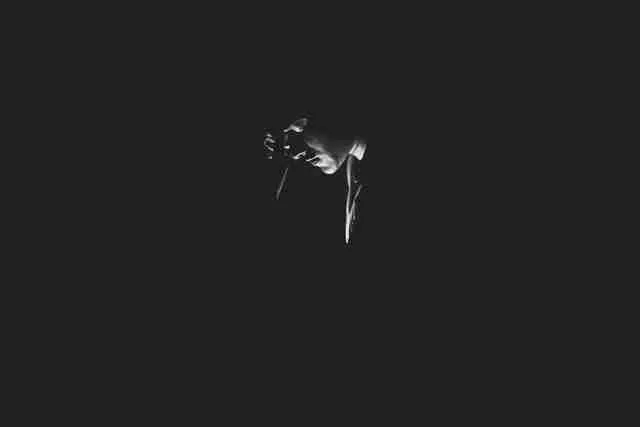 person shrouded in shadow and dimly illuminated in emotional pain