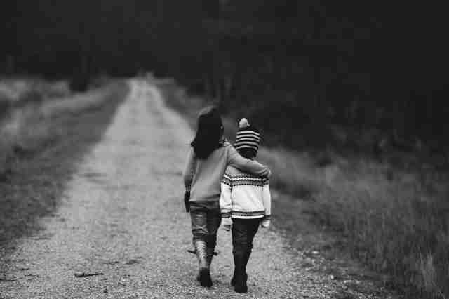 girl with empathy puts arm around preschooler while walking down the road