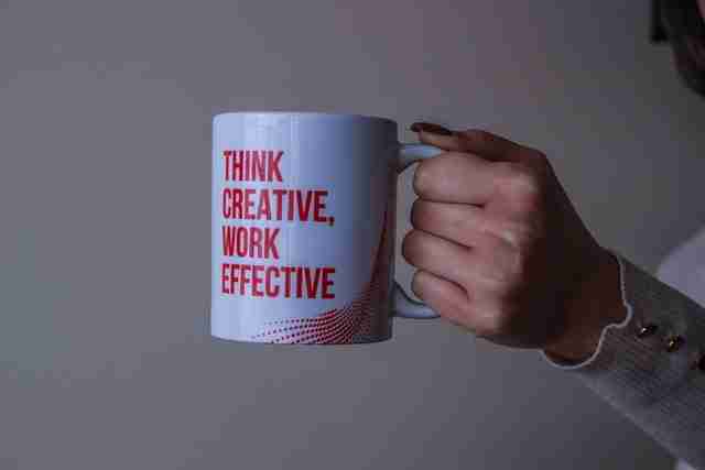 woman holding a white mug with the personal effectiveness saying, think creative, work effective