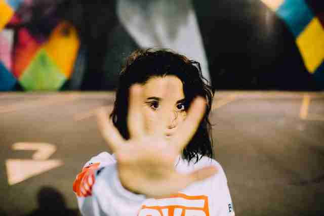 woman with her arm reaching out and her hand facing palm side out in a stop gesture