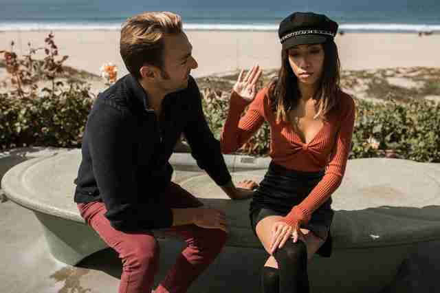 man pleading with woman as she holds a hand up to his face in a controlling relationship