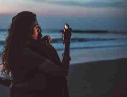 woman with a lack of empathy embracing man while secretly looking at her phone