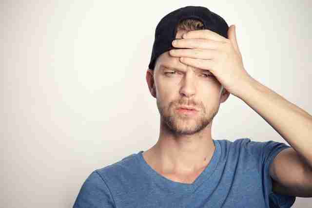 man rubbing his forehead in exasperation after dealing with difficult people