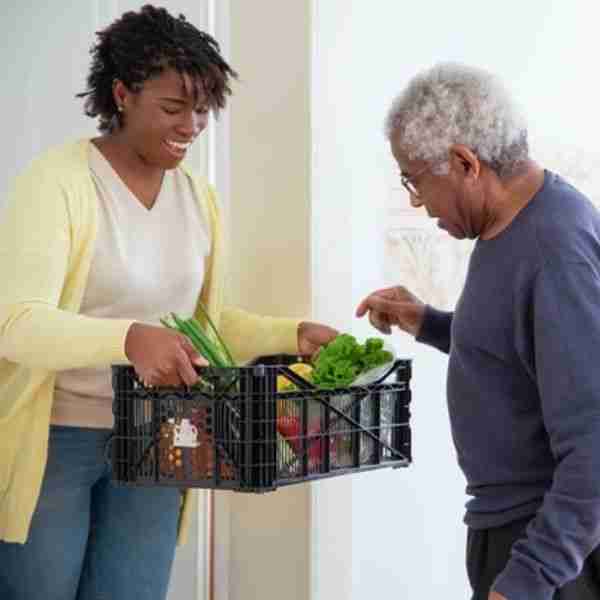 woman offering box of fresh vegetables to a man showing things good people do